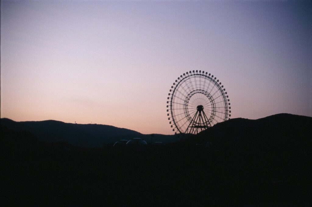 A silhouette of a ferris wheel on a mountain ridge.